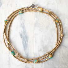 Load image into Gallery viewer, Warm sands, open vistas, blue sky.  Turquesa de la Tierra.  Turquoise of the Earth in Espanol.  Named for the beautiful Campitos turquoise from Mexico and the earthy handmade Columbian Clay beads, Turquesa de la Tierra exudes a warm, comforting energy.  Turquesa also features sandcast beads from Ghana, and matte 24k gold plated glass from Japan. Wraps may be worn as a necklace, choker, bracelet or anklet. US made magnetic clasp for easy styling.
