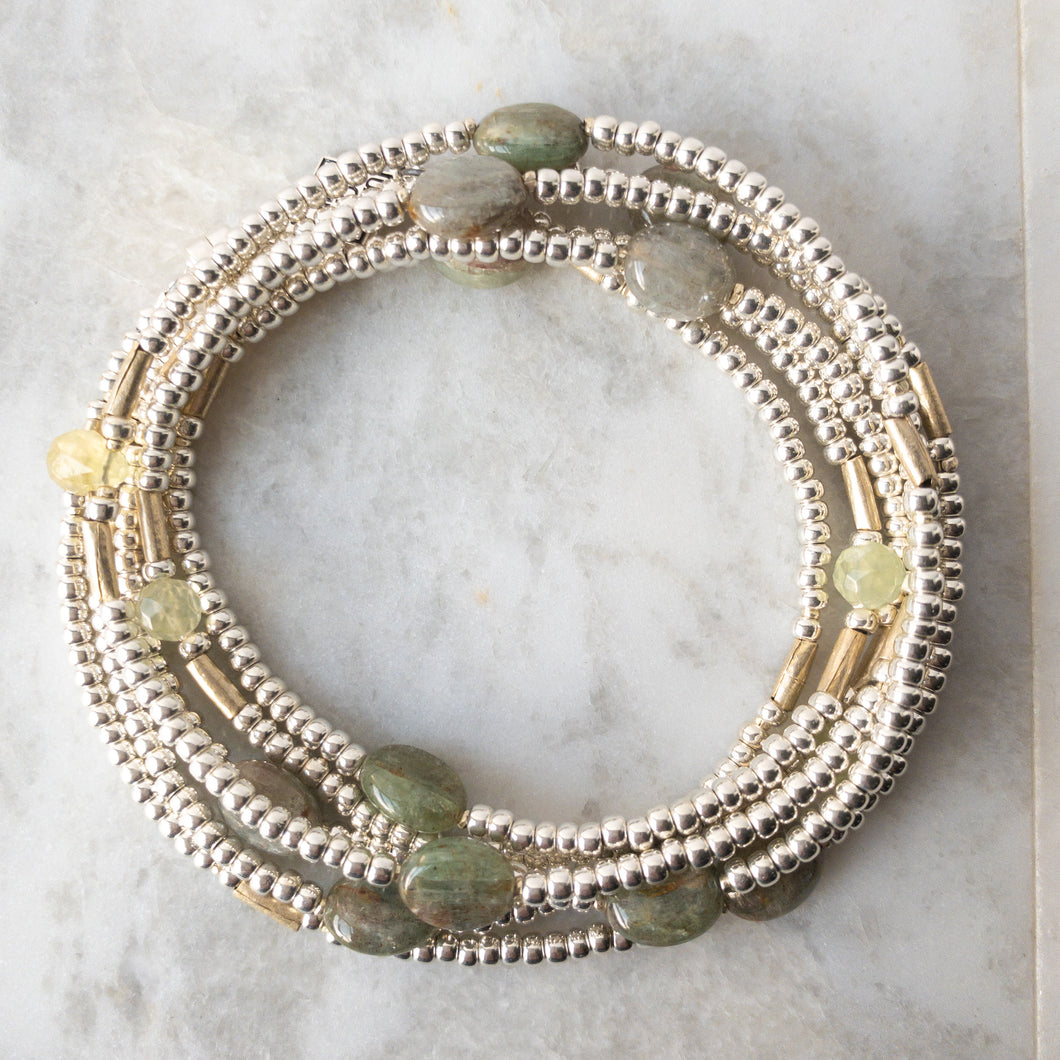 Green kyanite and prehnite imbue this wrap with soft, balanced energy.  Each prehnite drop is accented by dainty, fine silver beads handmade by the Karen Hill Tribe of India.  Adding depth are handmade 'white metal' tubes from Ethiopia, that will darken with age, highlighting the rutilation in the kyanite.  It's all about balance and looking into the future...Wraps may be worn as a necklace, choker, bracelet or anklet. US made magnetic clasp for easy styling.
