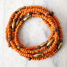 Load image into Gallery viewer, Rosewood&#39;s warmth may be drawn from not just it&#39;s beautiful red-brown color, but it&#39;s association with the Heart Chakra and it&#39;s healing properties.   Although you may not have a bed made of rosewood in which to rest, perhaps a wrap to adorn yourself with will do!The Heart and Healing wrap pairs lovely rosewood with vibrant, brick orange Ghana Goomba seed beads (handmade) and handmade Ethiopian brass beads.  A simple, yet substantial statement and an uplifting color for your spirits.
